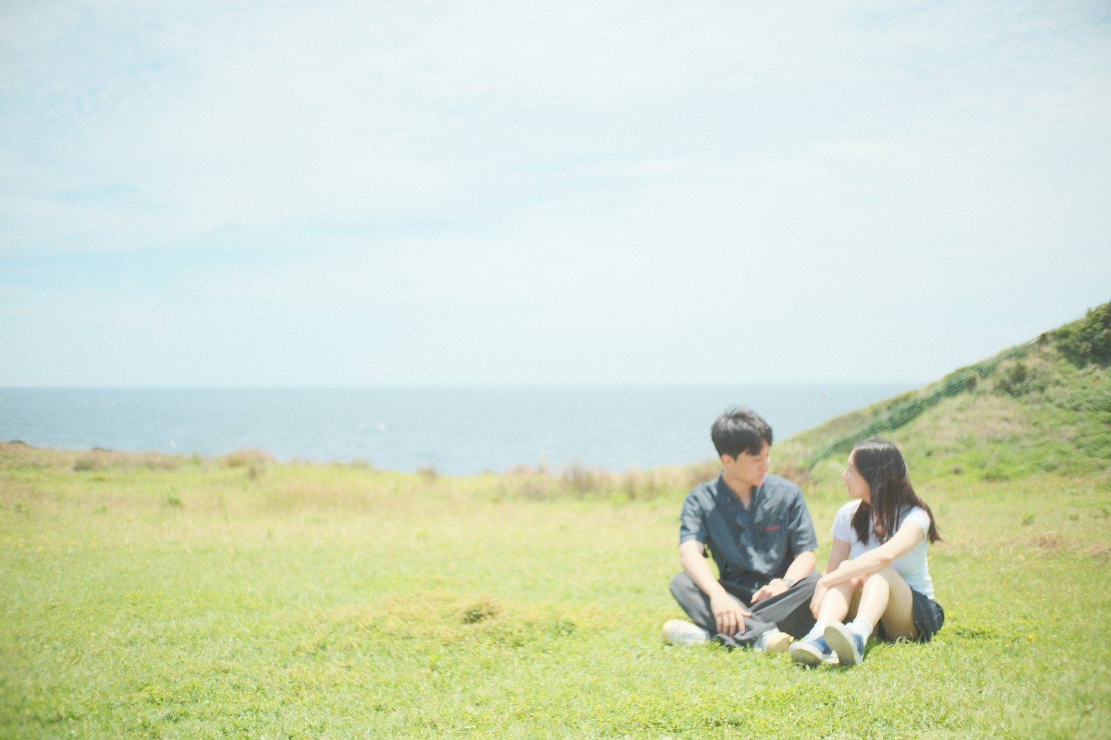 바다가 보이는 풀밭에 마주 앉은 두 사람
